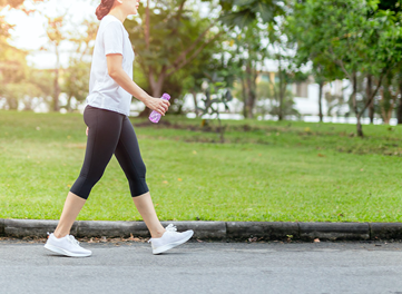 woman walking in park with drink bottle in hand