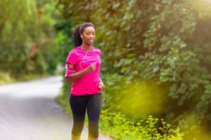 Lady jogging along a path surrounded by bushes