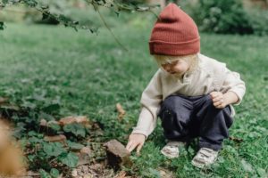 Young child squatting in garden touching grass