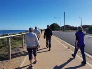 four people walking in sunshine along path