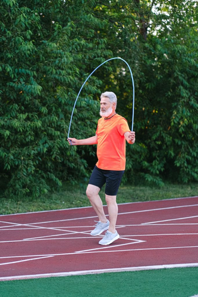 Older man in a orange tshirt skipping with skipping rope outside