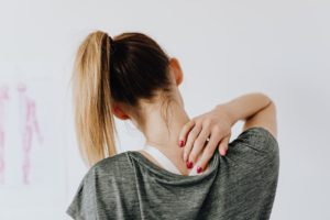 lady with pony tail rubbing her neck pain