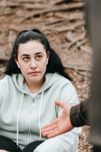 Lady wearing hoodie and another person holding their hand out.