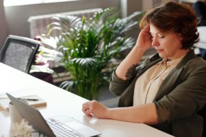 Lady tired holding head sitting at desk