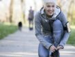 Woman kneeling to tie sho laces on a path in running clothes.