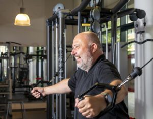 Man smiling pressing cable weights in gym