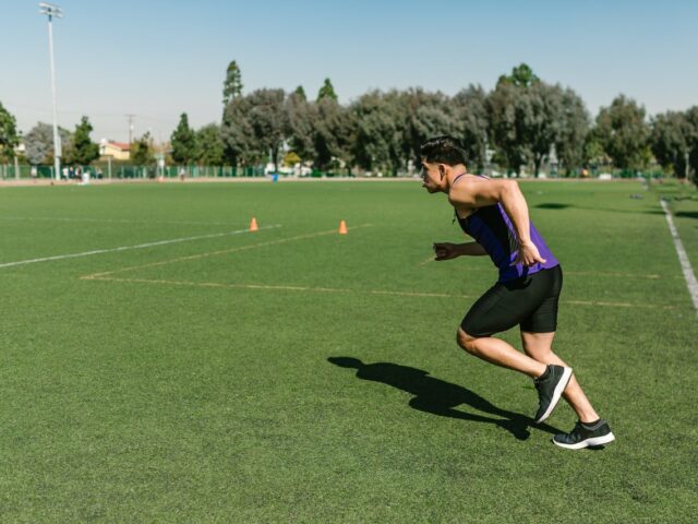 Man wearing active clothes running on grass sports field