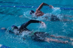 Two people swimming freestyle laps in pool