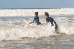 child surfing learning from father in ocean and waves