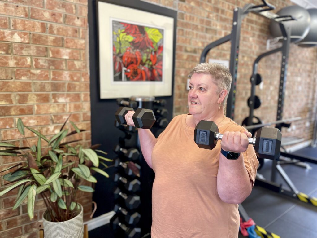 Woman in gym doing bicep curls with dumbbells